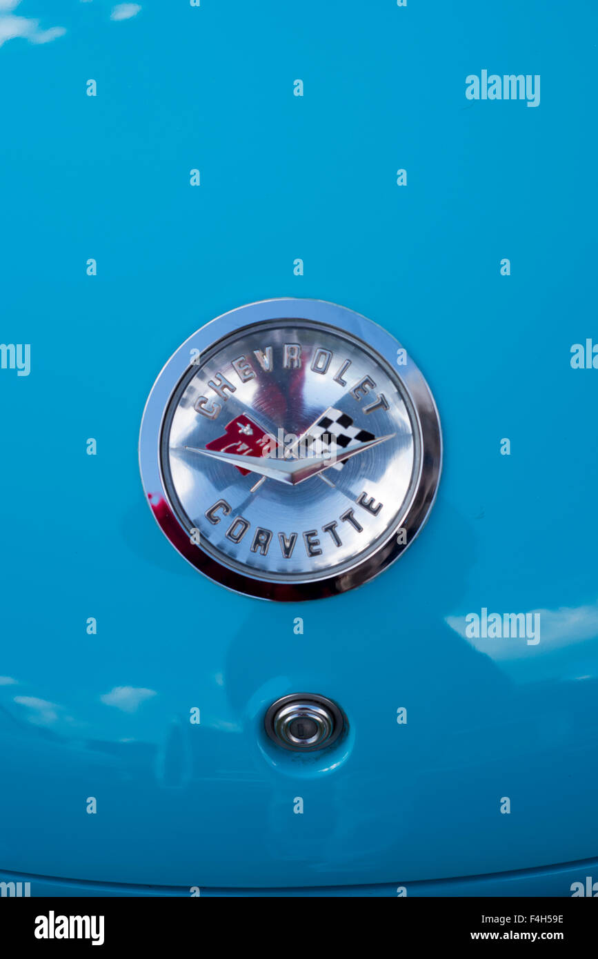 Little Blue Corvette, Chevrolet, silver badge, circle, flags, red, black, reflection, clouds, lock Stock Photo