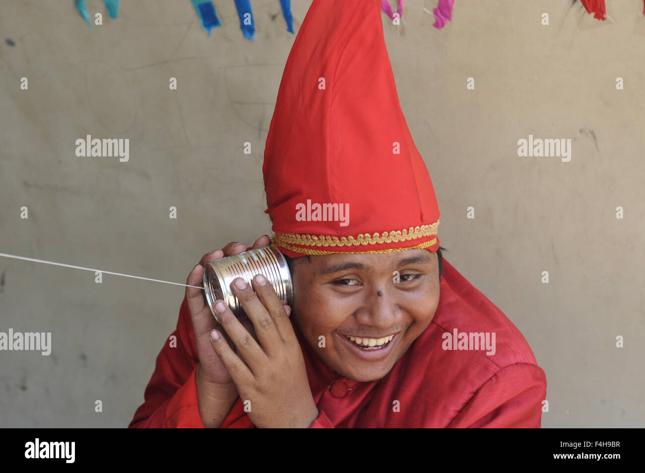 Makassar, Indonesia. 18th Oct, 2015. Indonesian teenager tries to hear the sound using thread phone at Traditional Games Festival in Makassar, Indonesia on October 18,2015. This festival was held to introduce kinds of traditional games played by Makassar kids in the past. Many traditional games in Indonesia have been dissapeared in this modern world due to the advancement of technology that offer many games through cellphones and video games. Most of Indonesian traditional games are physical games that can improve child psychomotor learning. Credit:  Yermia Riezky Santiago/Alamy Live News Stock Photo