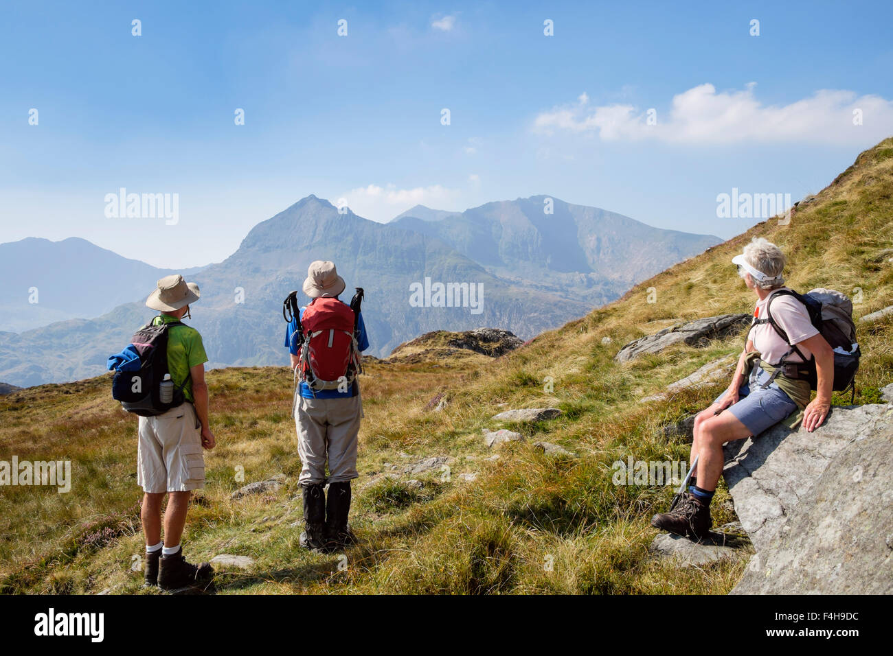 Three senior hikers looking back at Snowdon horseshoe from hiking on Red Route up Glyder Fawr in mountains of Snowdonia National Park Eryri Wales UK Stock Photo