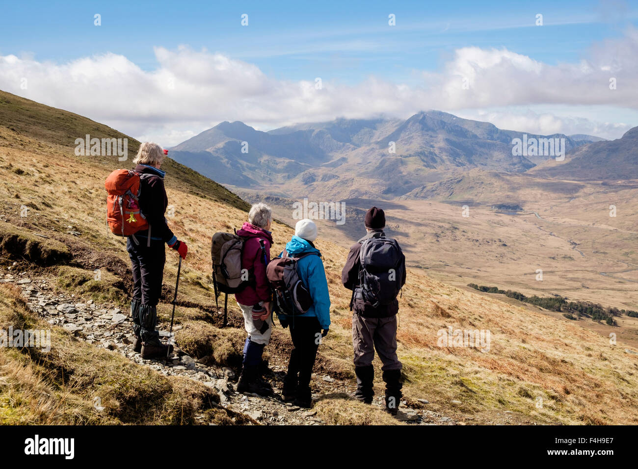 Four hikers look at view to Mount Snowdon Horseshoe whilst hiking on path from Moel Siabod to Capel Curig in mountains of Snowdonia (Eryri) Wales UK. Stock Photo