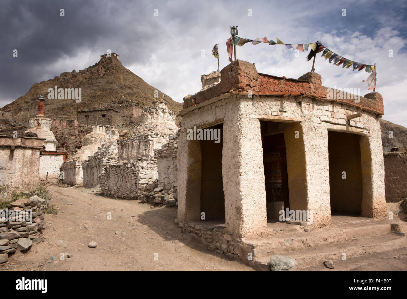 India, Jammu & Kashmir, Ladakh, Miru, old chortens and prayer wheel enclosure below hilltop temple Stock Photo