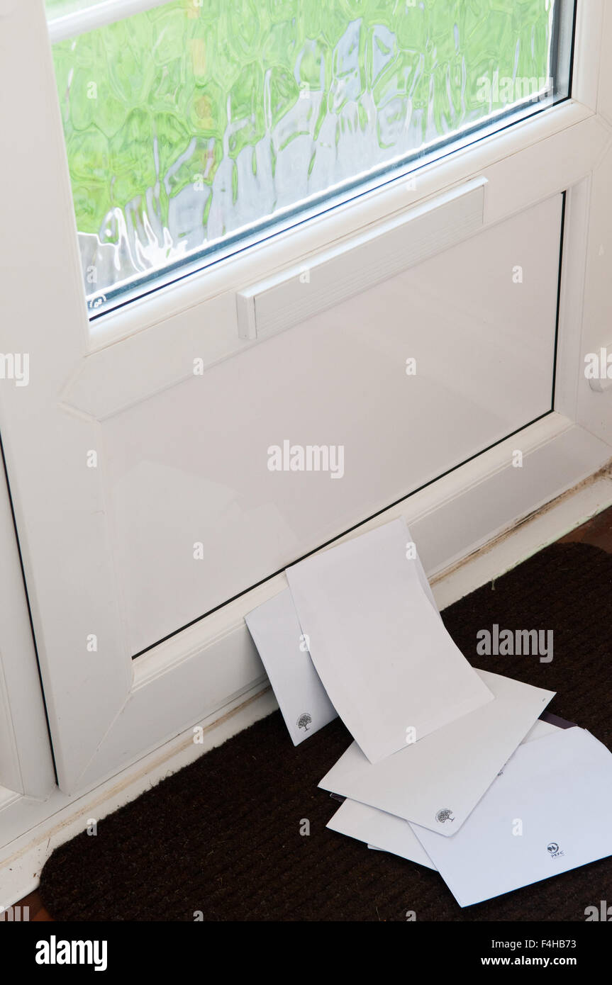 Unopened mail piled up on the door mat Stock Photo