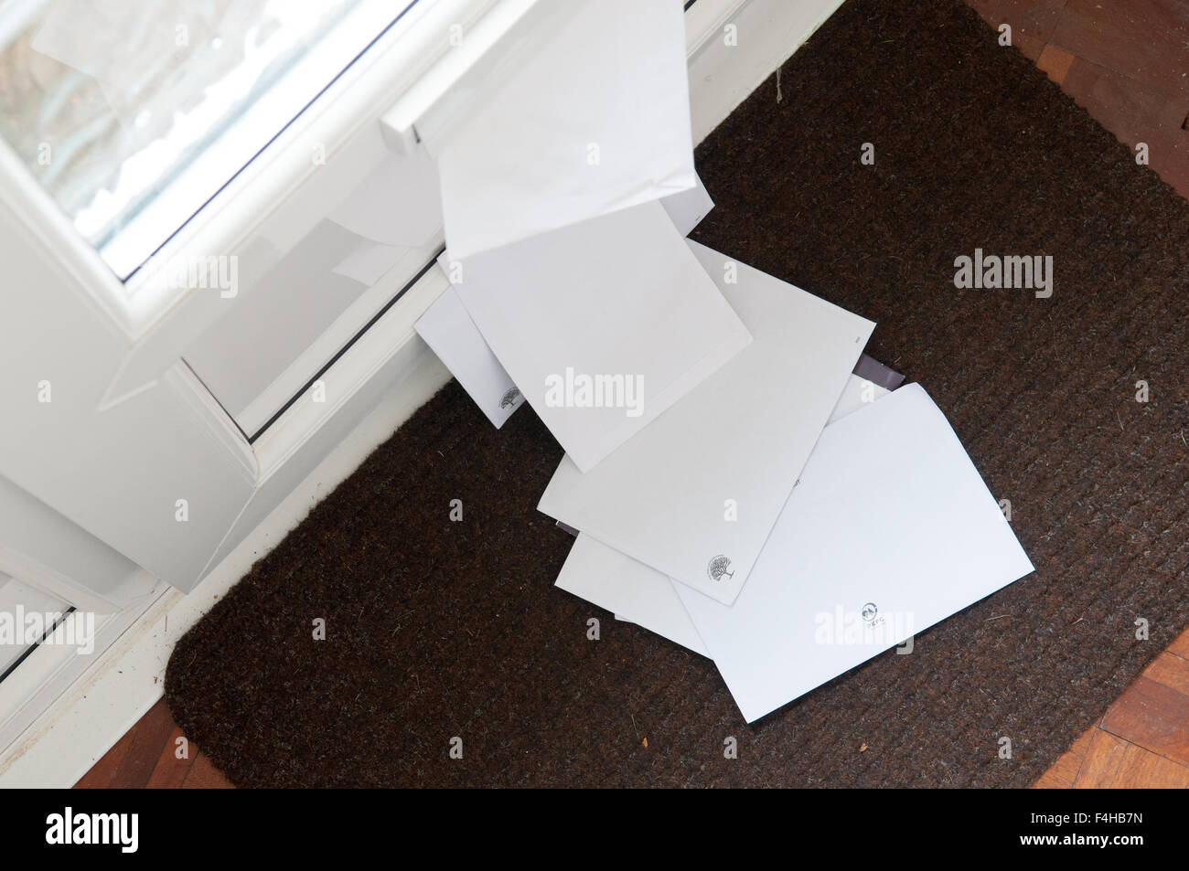 Unopened mail piled up on the door mat Stock Photo