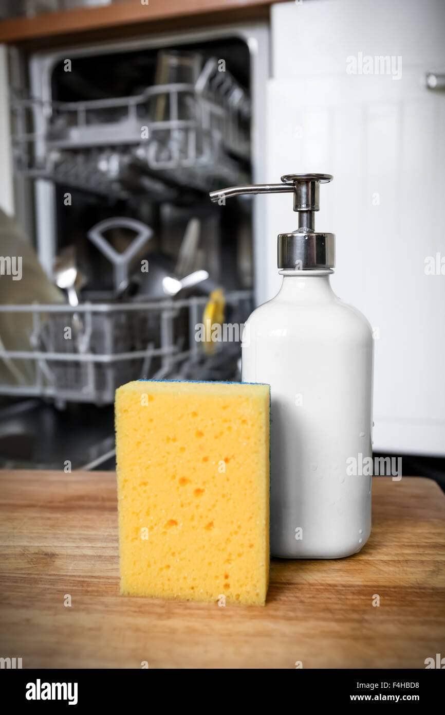 Dishwasher sponge with soap in dispenser tube on background of opened