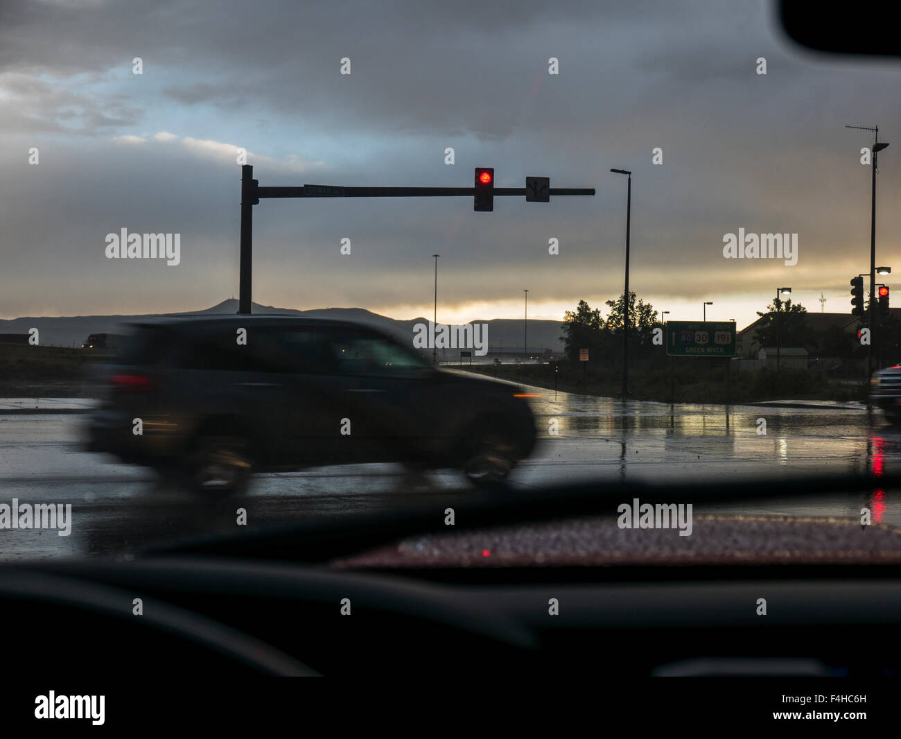 Windshield view of automobile moving through intersection; rain storm
