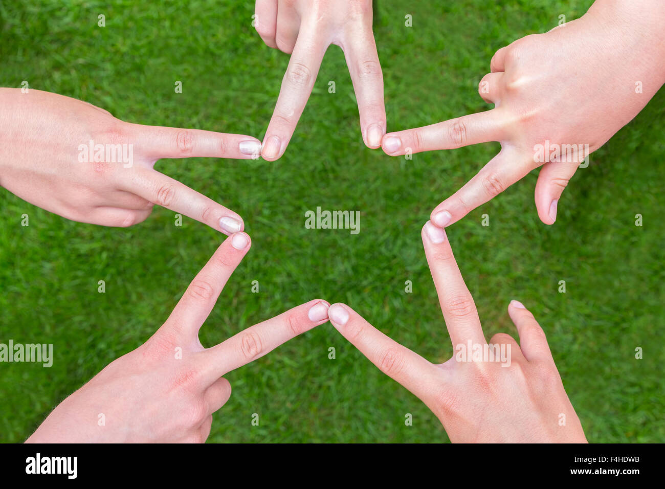 Five hands of teens making star shape together above grass Stock Photo