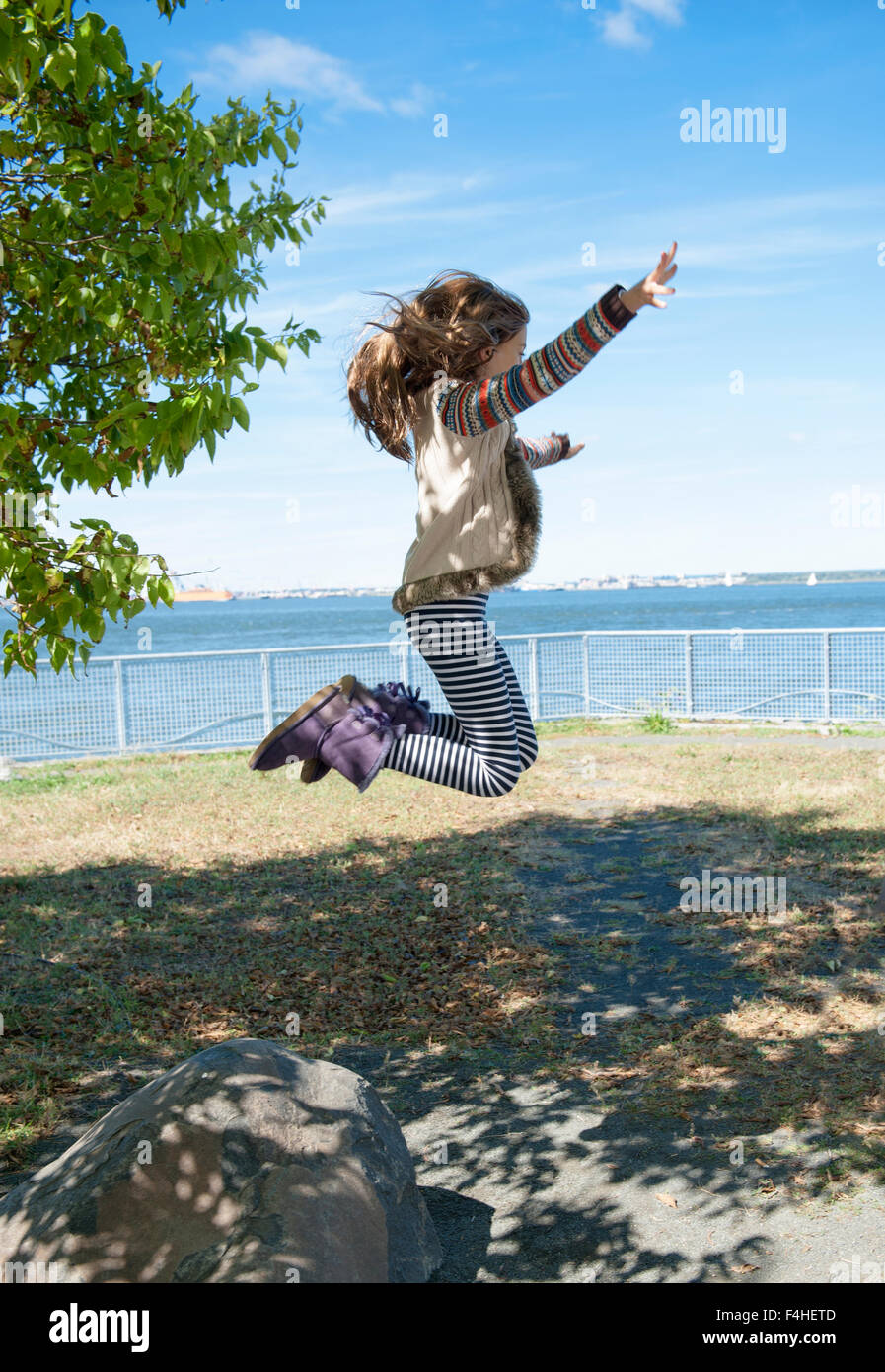 Little girl jumping up in the air with blue sky Stock Photo