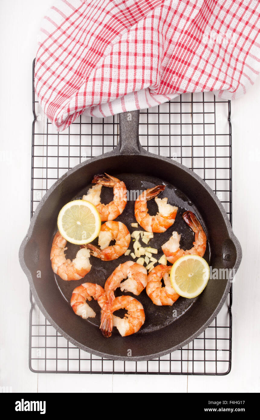 grilled king prawns with lemon slice and crushed garlic in a cast iron
