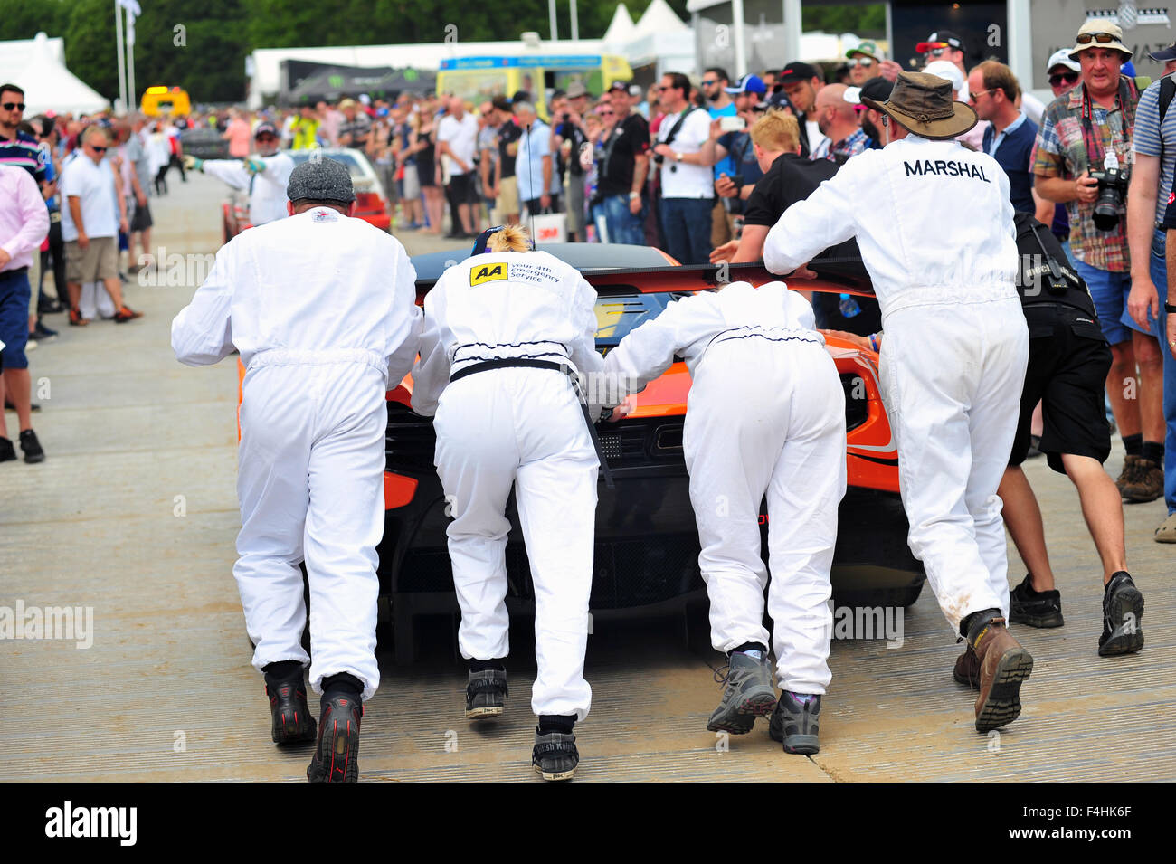 Marshals push a racing car past crowds at the Goodwood Festival of Speed in the UK. Stock Photo