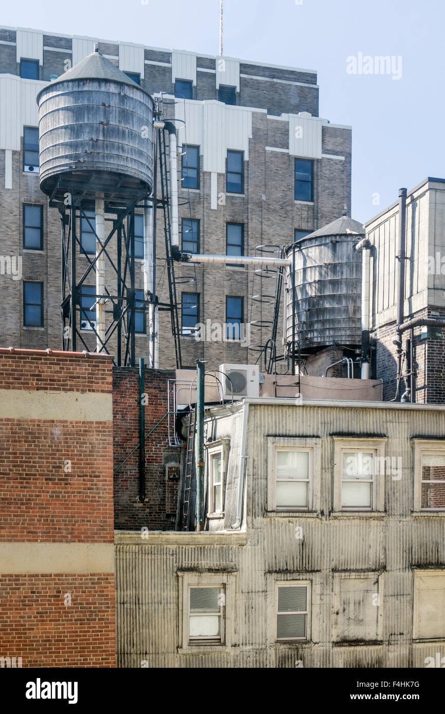 2 interconnected cylindrical wooden water towers resting on steel framework on roofs of adjacent buildings in downtown Manhattan Stock Photo