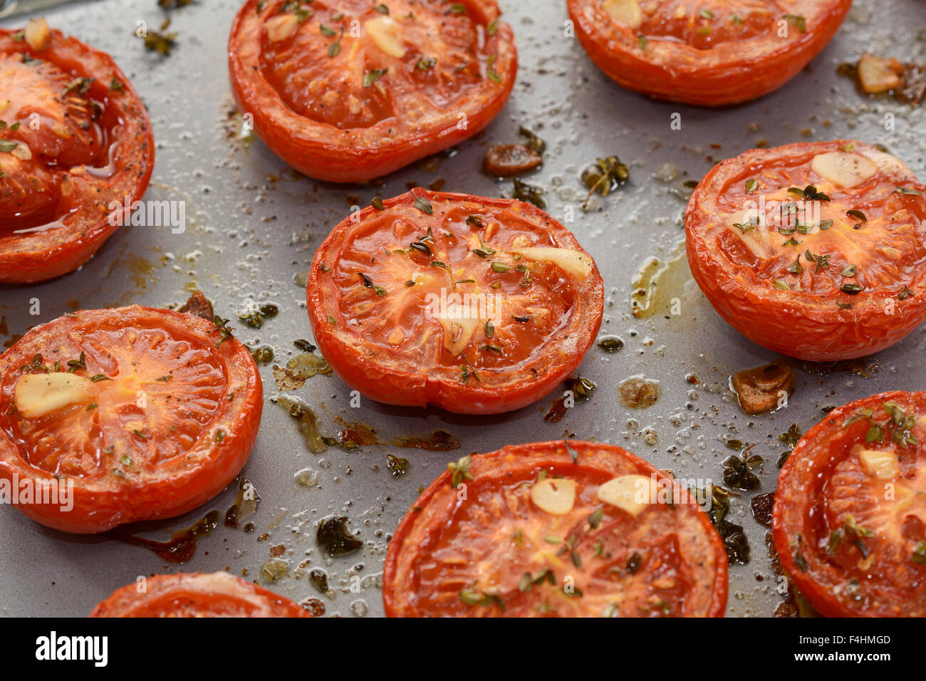 Close-up of roasted tomato halves, hot from the oven with garlic and thyme Stock Photo