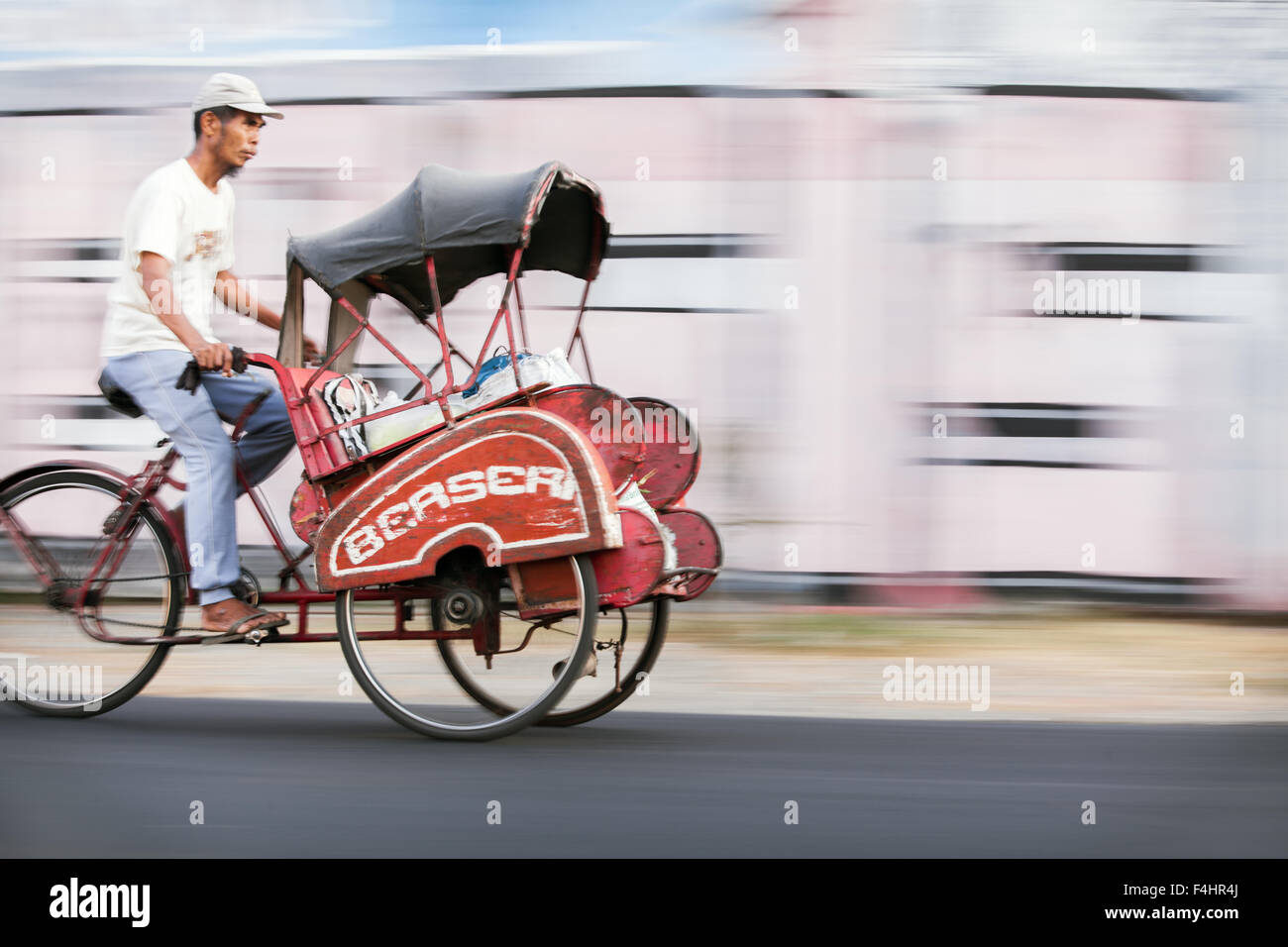 Panning photography photo of Indonesia Becak (Cycle Rickshaw) travelling at speed with a slow shutter effect creating a background motion blur Stock Photo