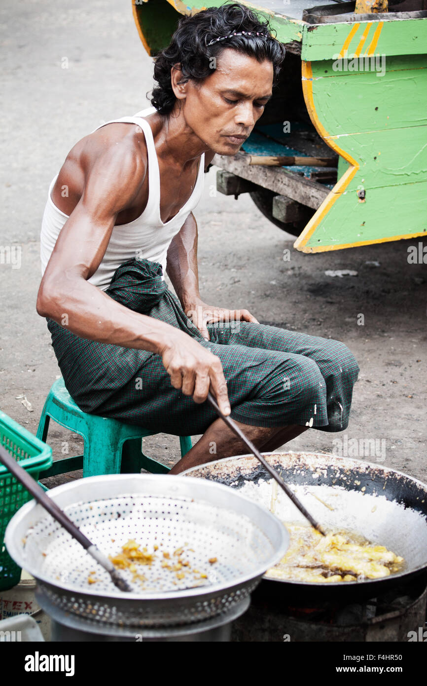 Street photography photo of Burmese man frying street food on the streets in Myanmar. Fast food, cheap snack food from a small business entrepreneur Stock Photo