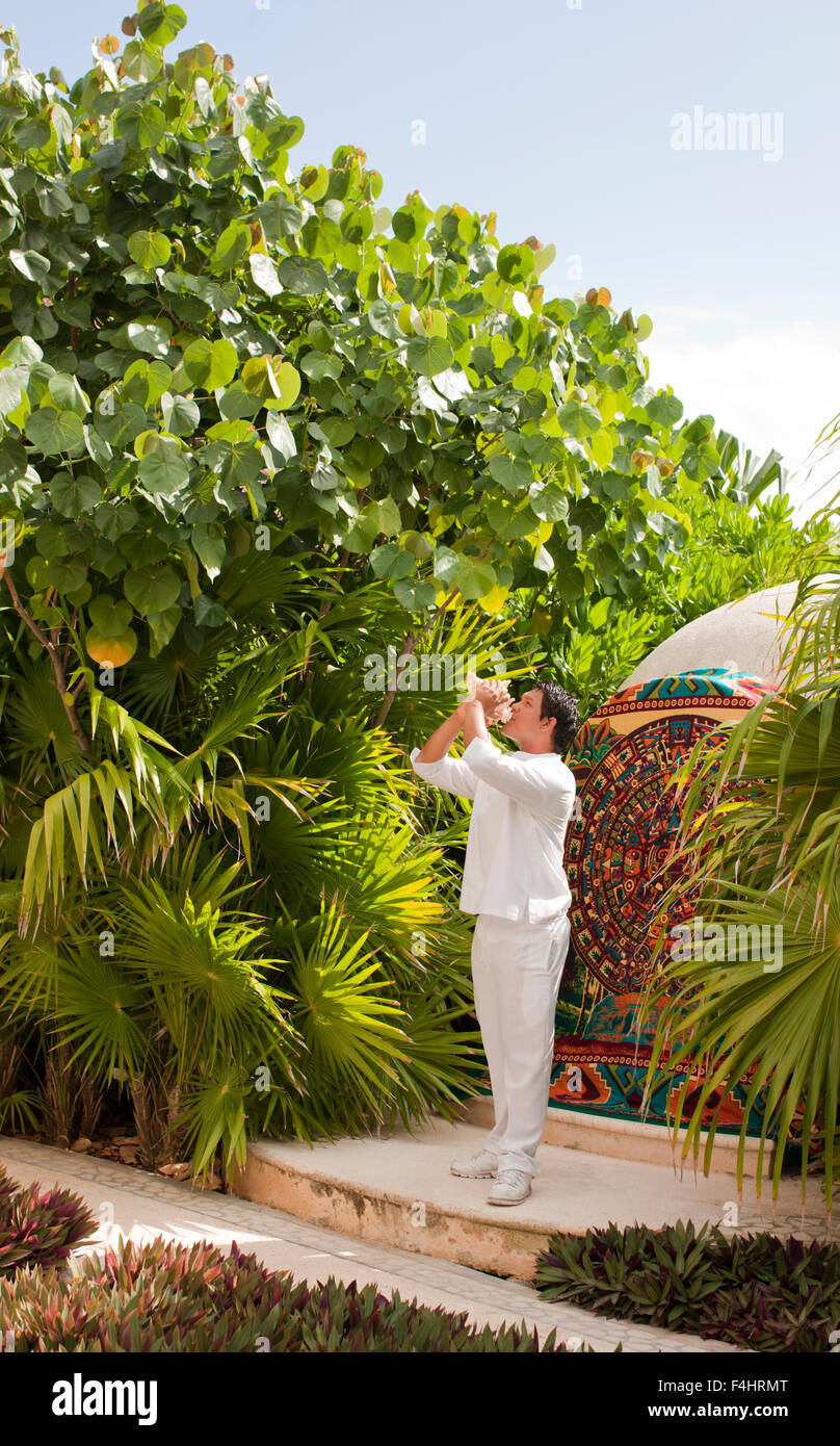 A young Mexican man blows a conch shell to signal the start of the Temazcal treatment at Spa Aqua at Live Aqua Resort & Spa. Stock Photo