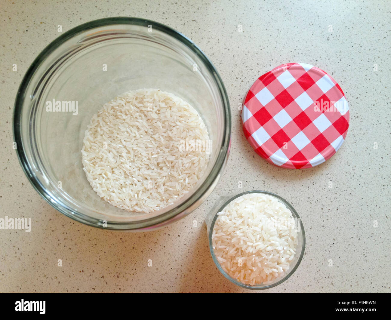 White rice in an open large glass jar and a glass full with chequered ...