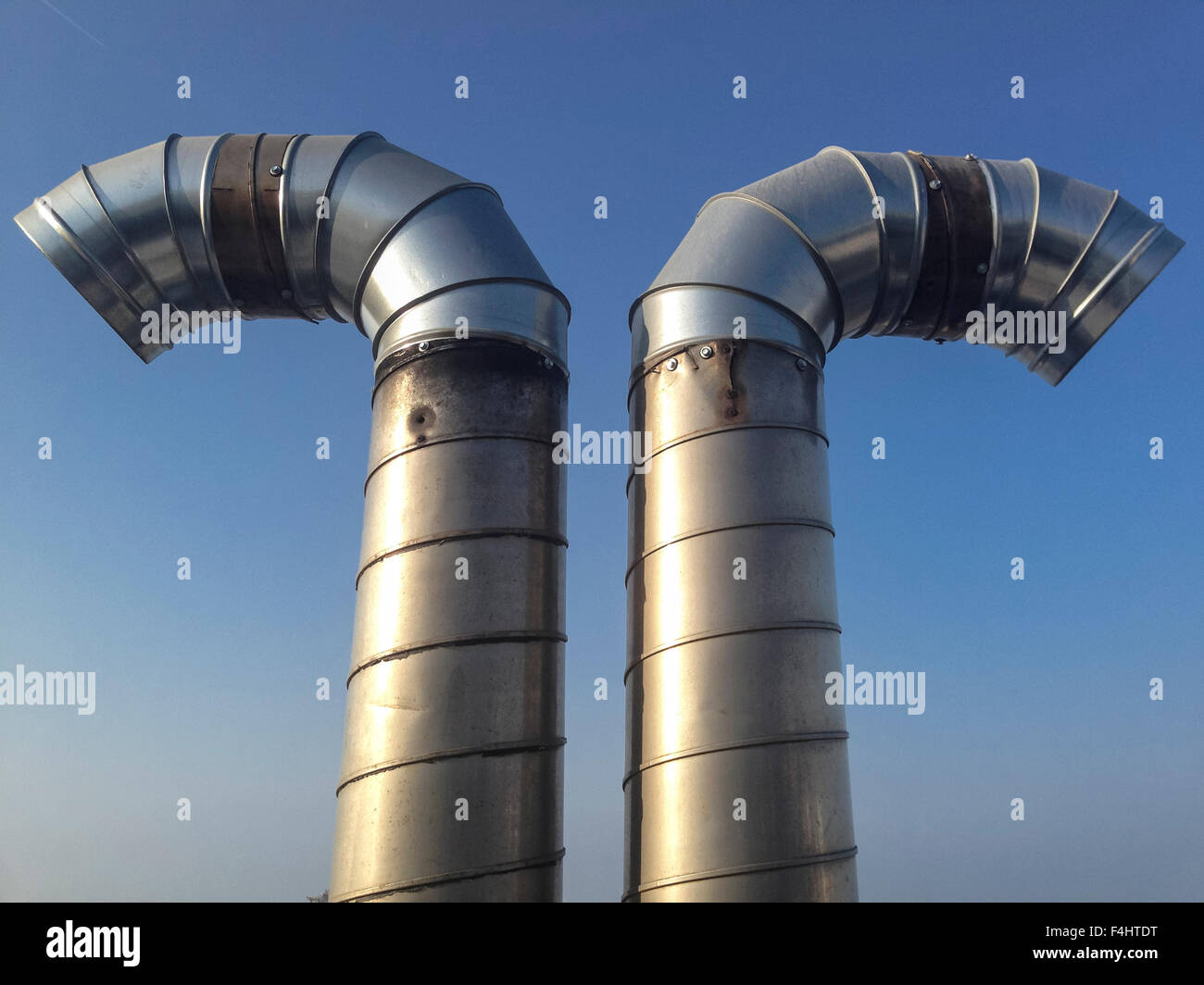 Curved steel pipes as smoke stack over blue sky Stock Photo
