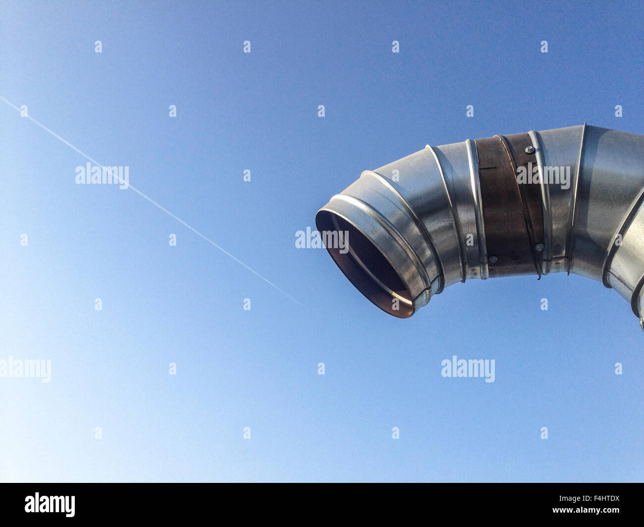 Curved steel pipes as smoke stack over blue sky Stock Photo