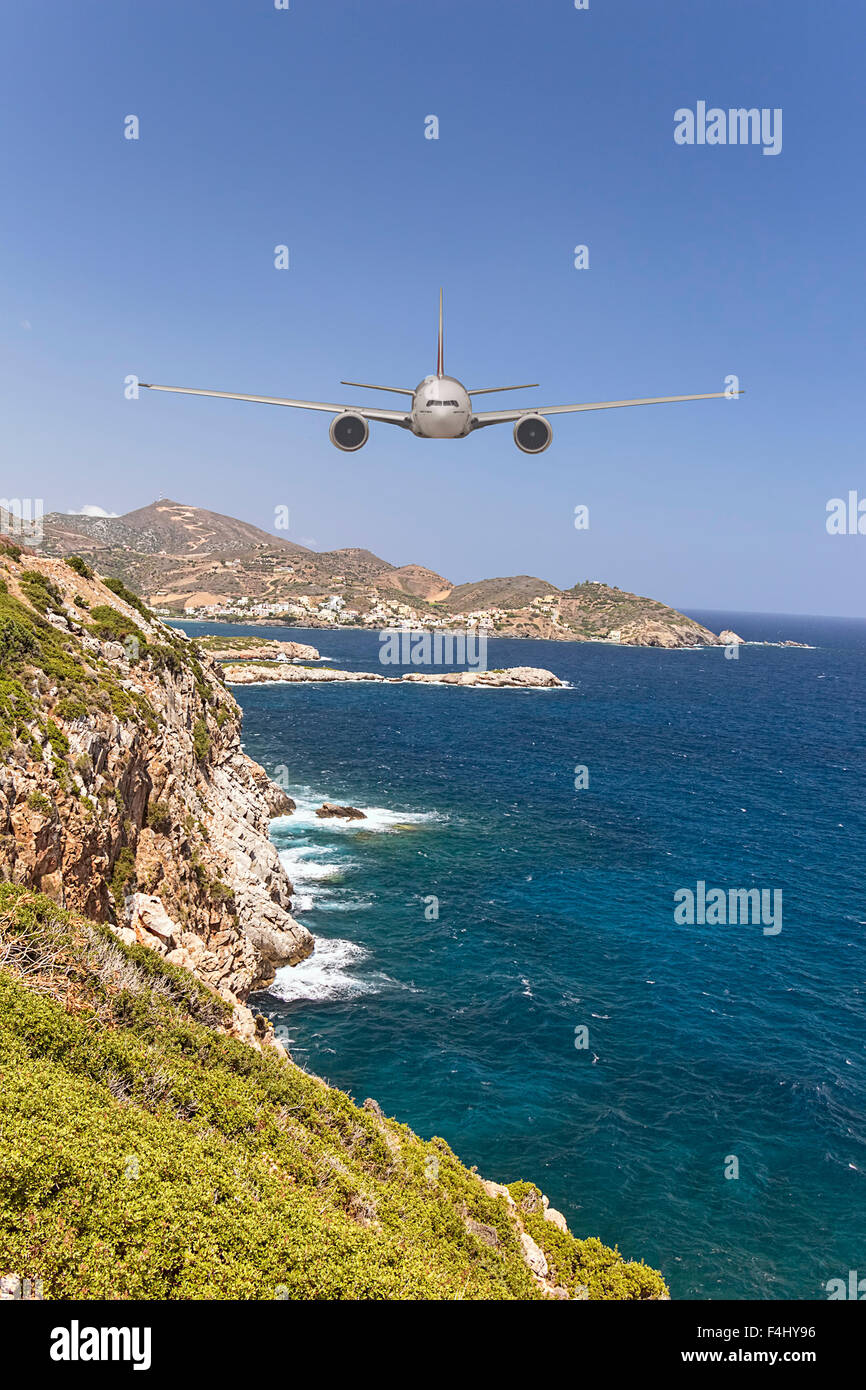 Passenger plane flying and approaching  head-on to and island over beautiful blue sea in summer vacation destination, going to l Stock Photo