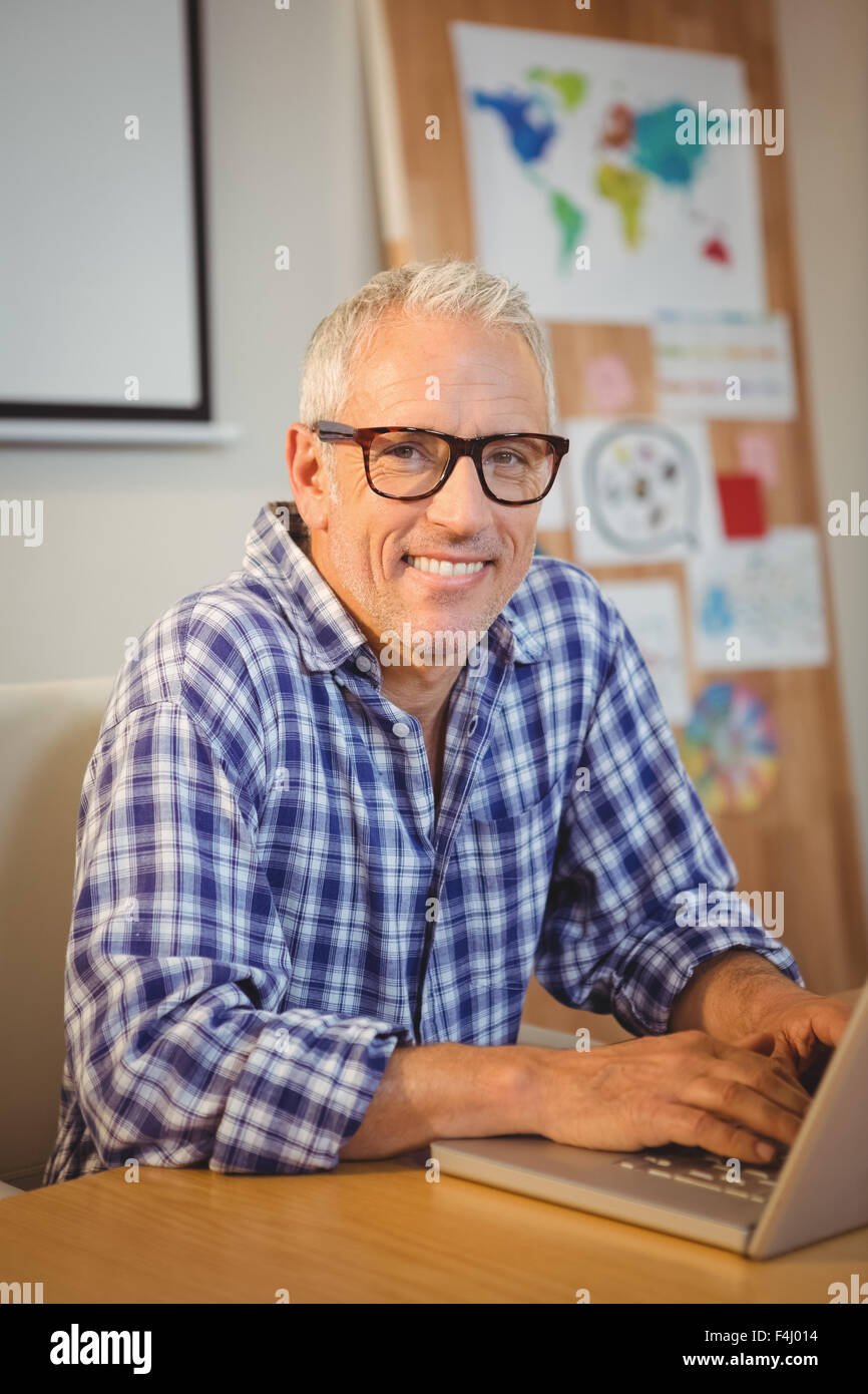 Portrait of happy creative businessman with eyeglasses using laptop Stock Photo