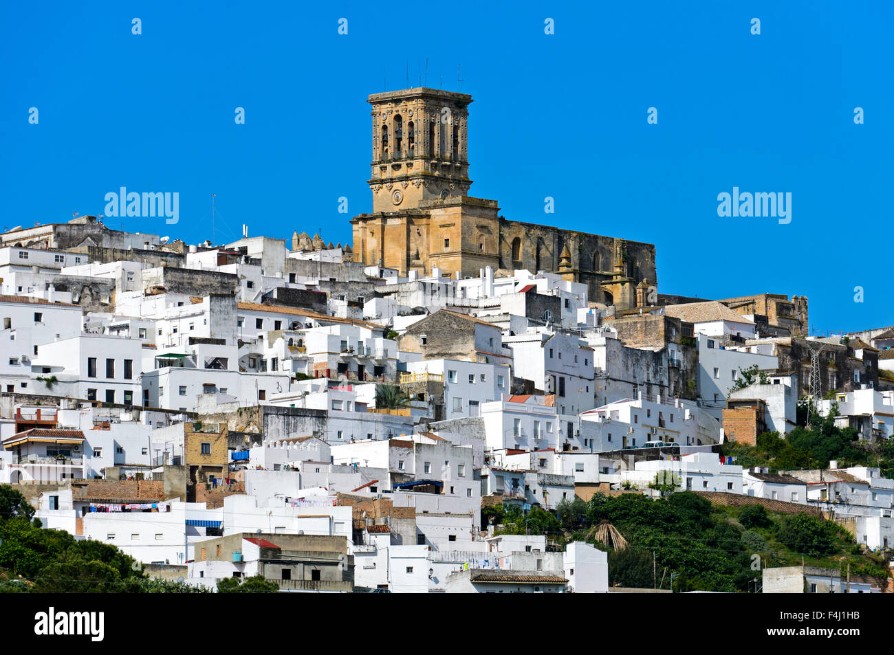 Basilica de Santa Maria de la Asuncion rises above the White Town, of Arcos de la Frontera, Andalusia, Spain Stock Photo