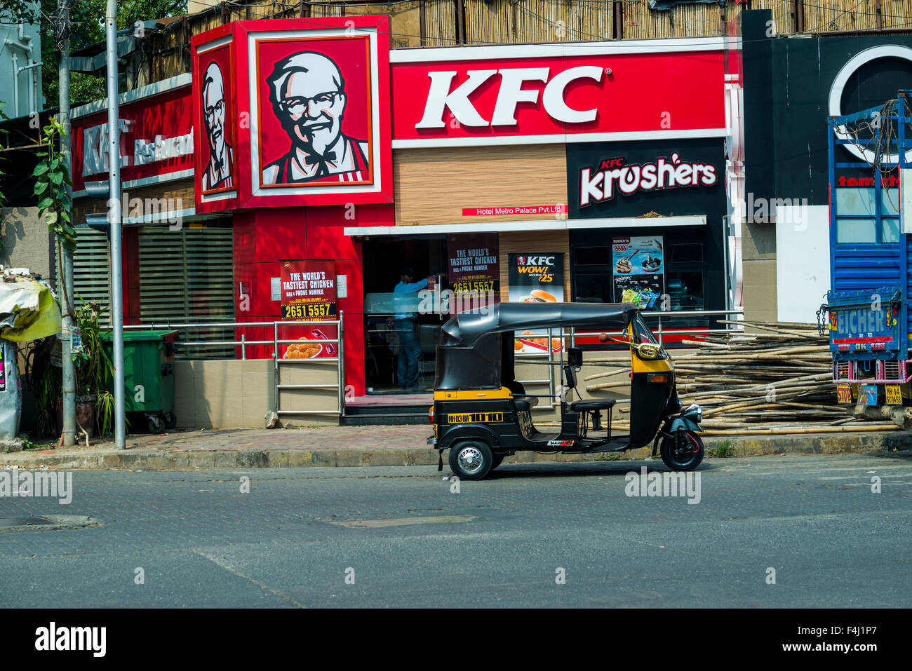 The red facade of a Kentucky Fried Chicken, KFC, restaurant with a motor rikshaw parking in front Stock Photo