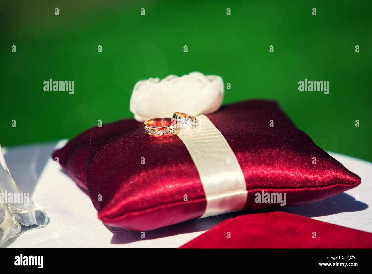 Wedding rings on a red cushion on a background of green grass Stock Photo