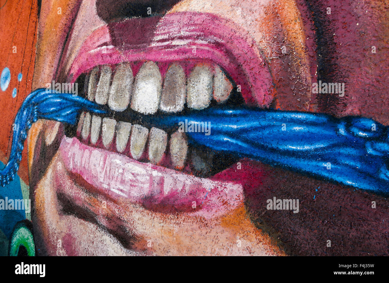 VALPARAISO, CHILE - OCTOBER 29, 2014: Colourful graffiti detail of an aggressive face with scarf between the teeth in Valparaiso Stock Photo