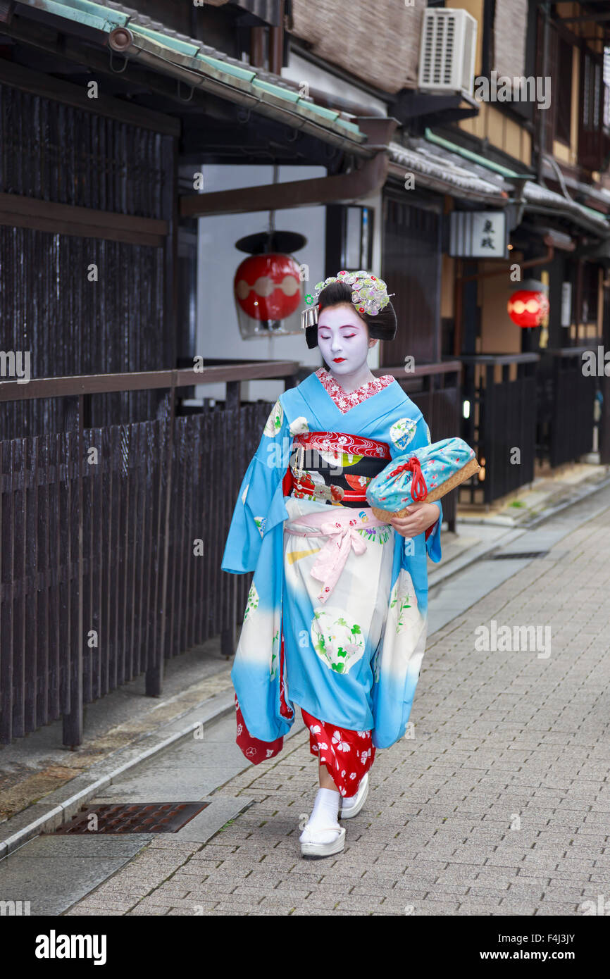 Maiko, apprentice geisha, walks to evening appointment past traditional wooden tea houses, Gion, Kyoto, Japan, Asia Stock Photo