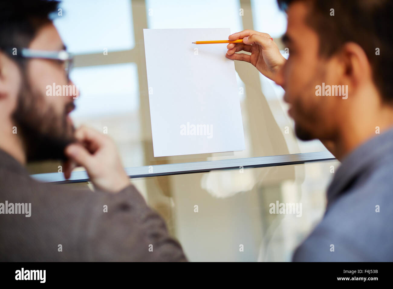 Businessman with pencil pointing at blank paper on board during
