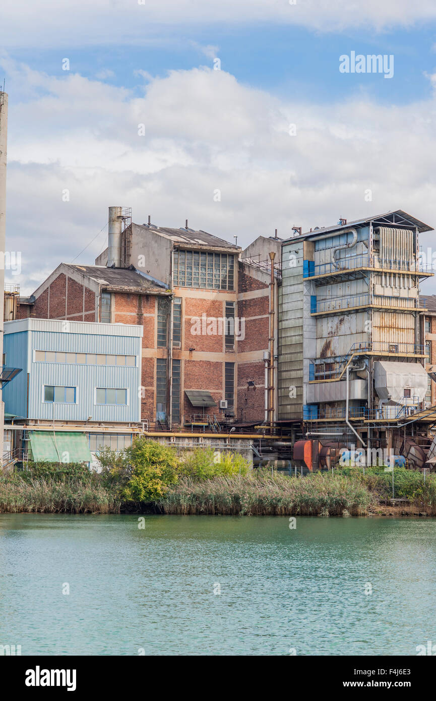 The old chemical factory with chimneys and silo on the banks of the river Stock Photo