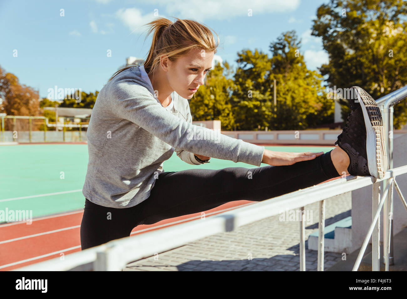 Portrait of a fitness woman stretching legs on outdoor stadium Stock ...