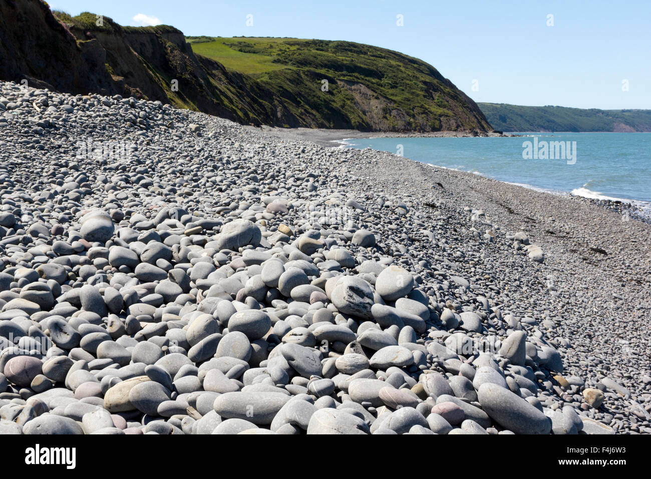 Pebbles at Greencliff Beach – A View at High Tide, Looking South West towards Bucks Mills, Devon, UK. Stock Photo