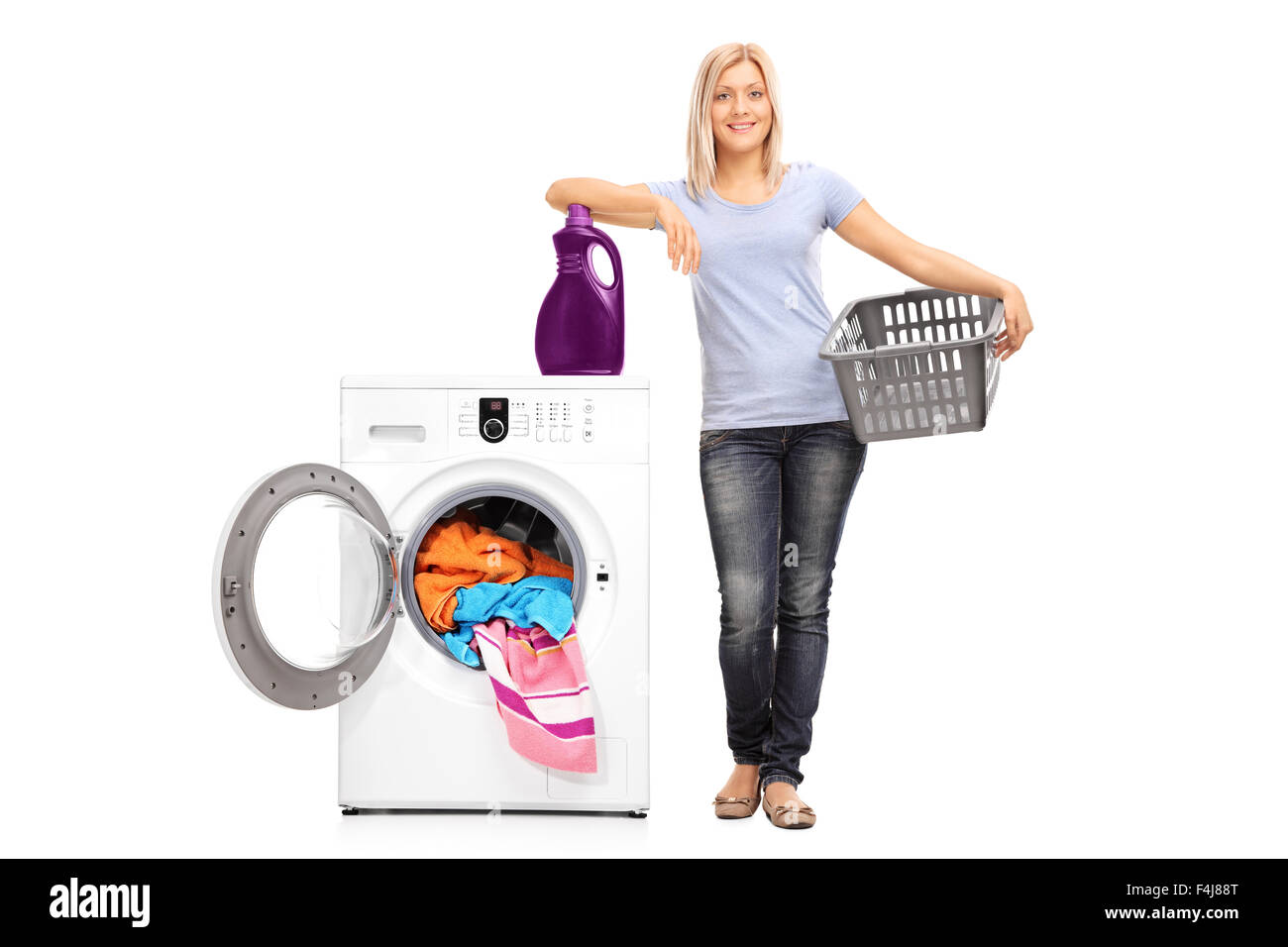 Full length portrait of a young woman holding an empty basket and leaning on a laundry detergent on top of a washing machine Stock Photo