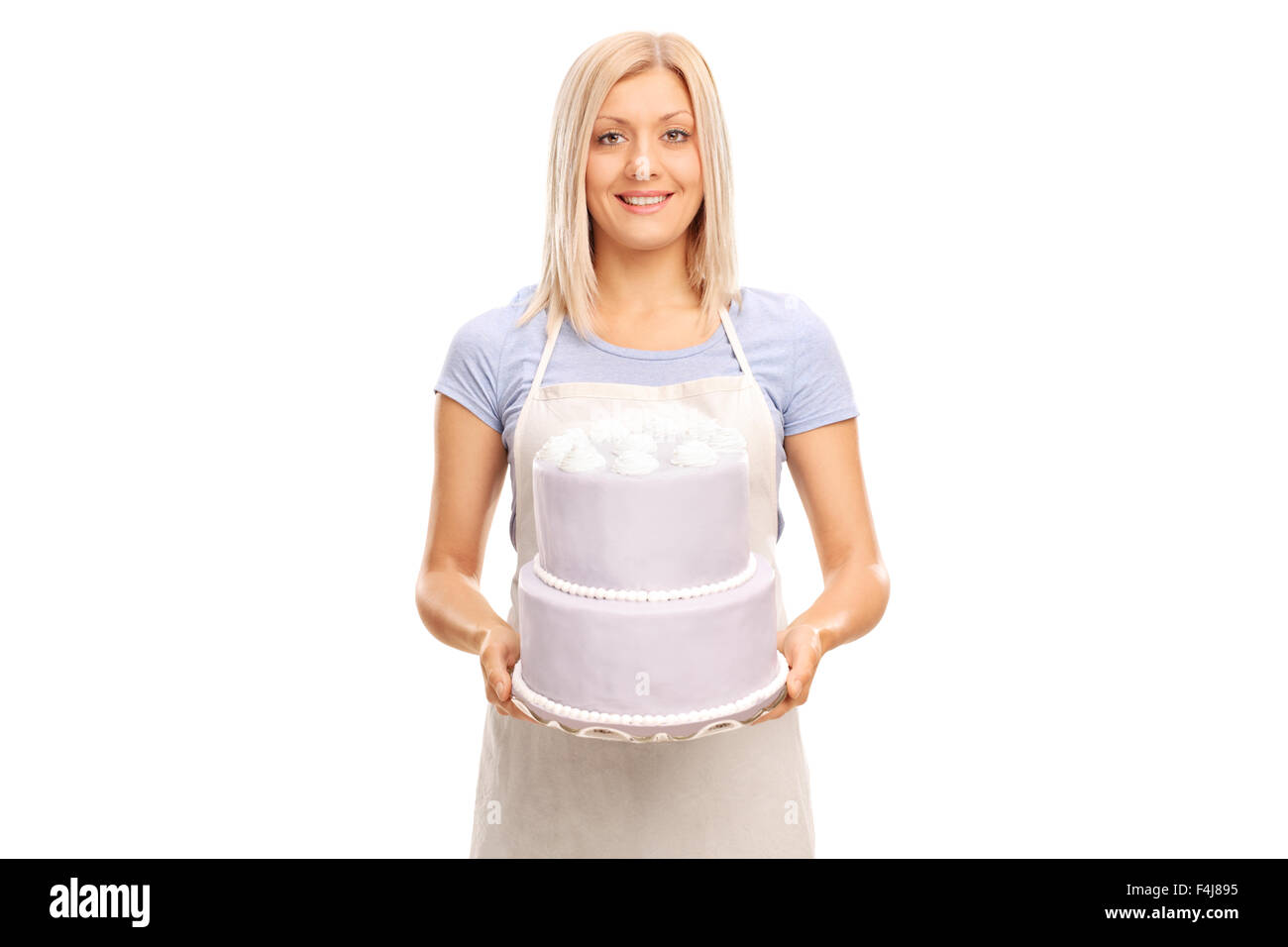 Studio shot of a blond female pastry chef carrying a large cake and looking at the camera isolated on white background Stock Photo