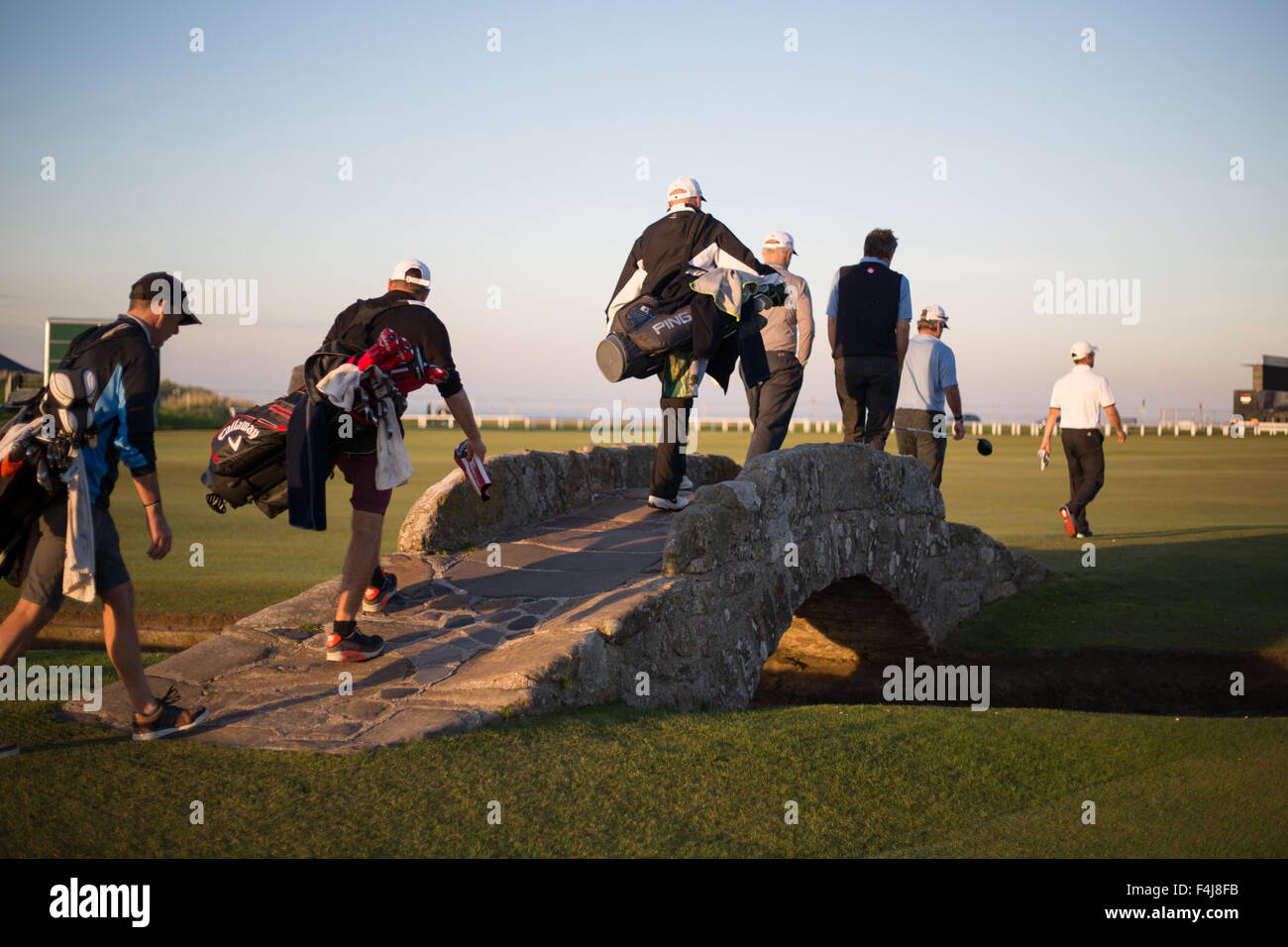 Golfers cross the world famous Swilcan (Burn) Bridge on the St. Andrews links golf Old Course, St. Andrews, Scotland, UK. Stock Photo