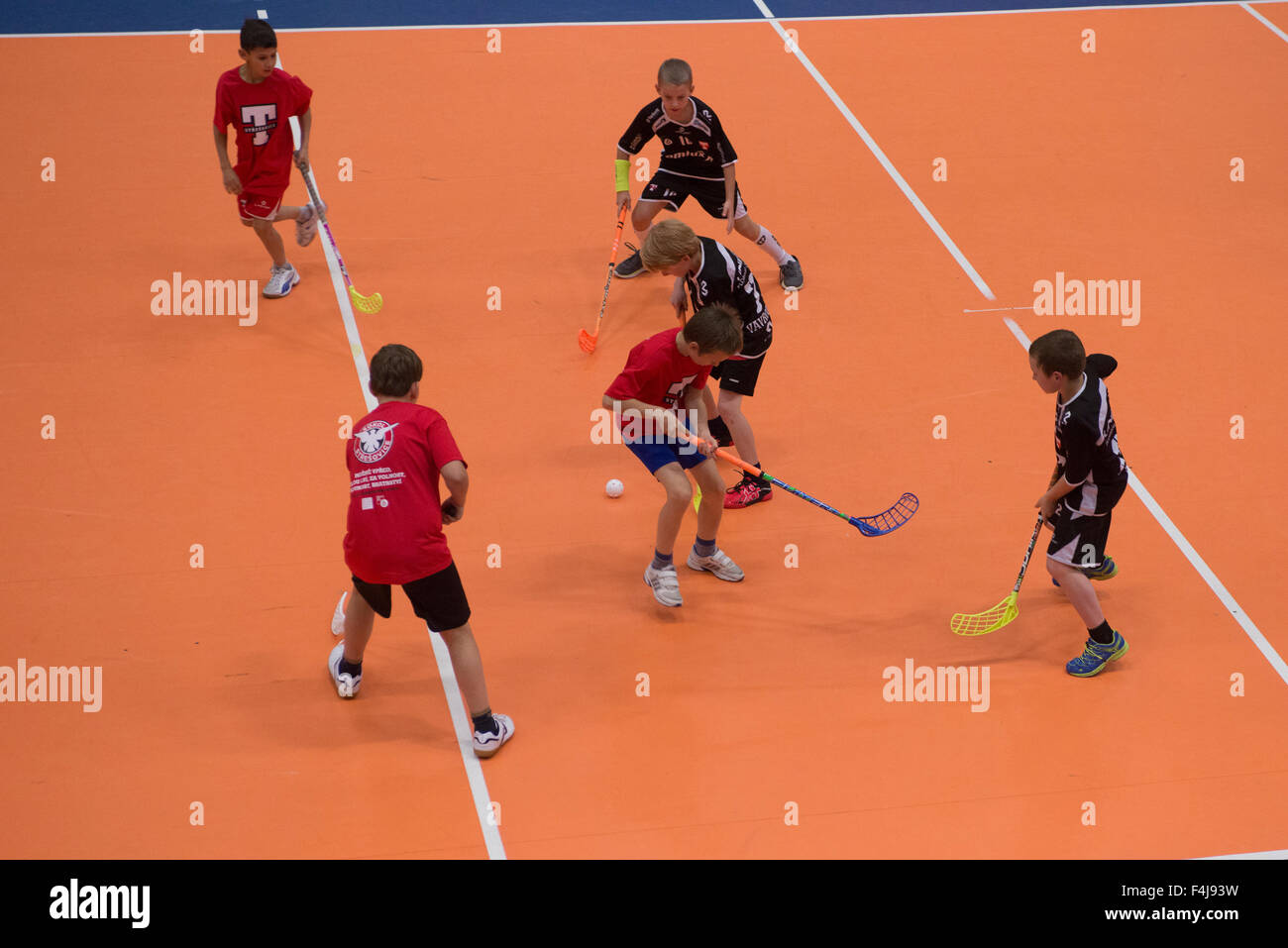 Children boys schoolchildren playing floorball (floor hockey) match in school gym sport hall