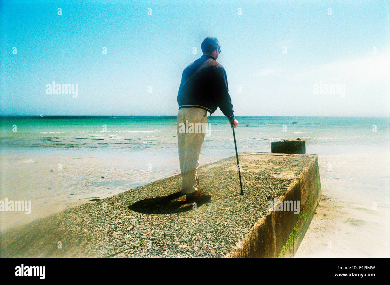 A man with a stick by the sea, France. Stock Photo