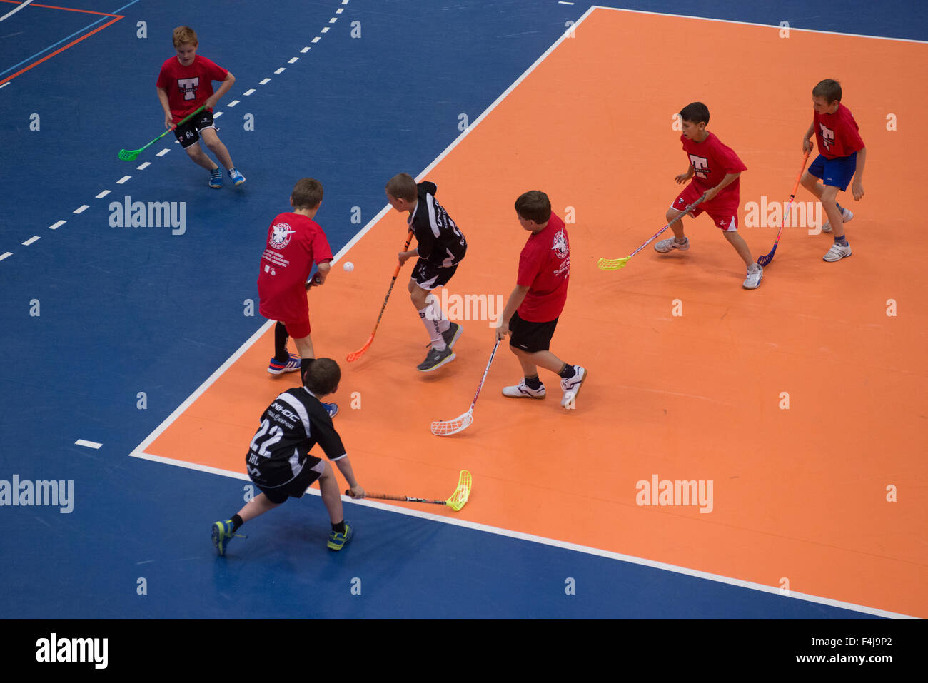Children boys schoolchildren playing floorball (floor hockey) match in