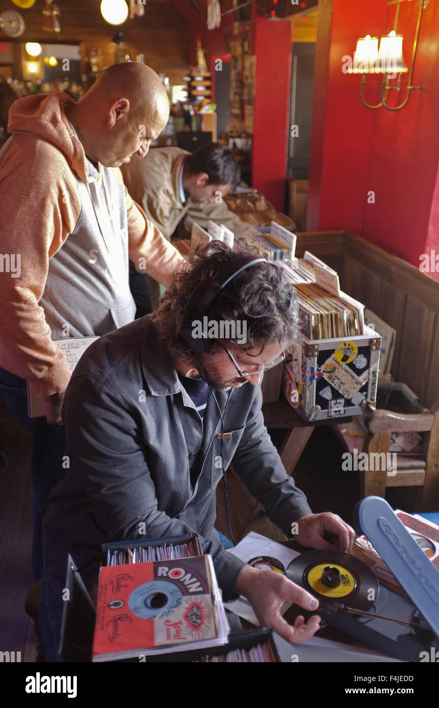 Two record collectors at a record fair looking through records. The man sitting checks out 45's on a portable turntable. Stock Photo