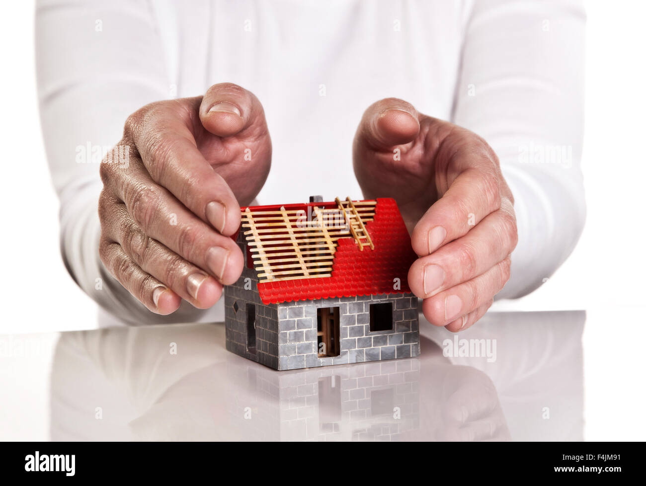 Hands close protectively around a new building. Stock Photo