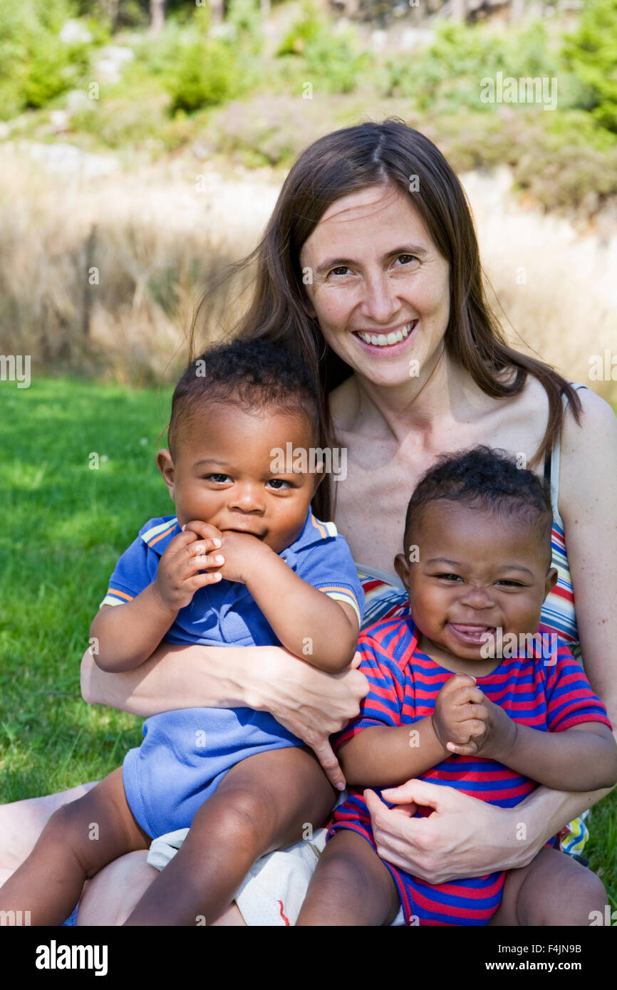 Sweden, Gothenburg, portrait of mother embracing sons (12-17 months) outdoors Stock Photo