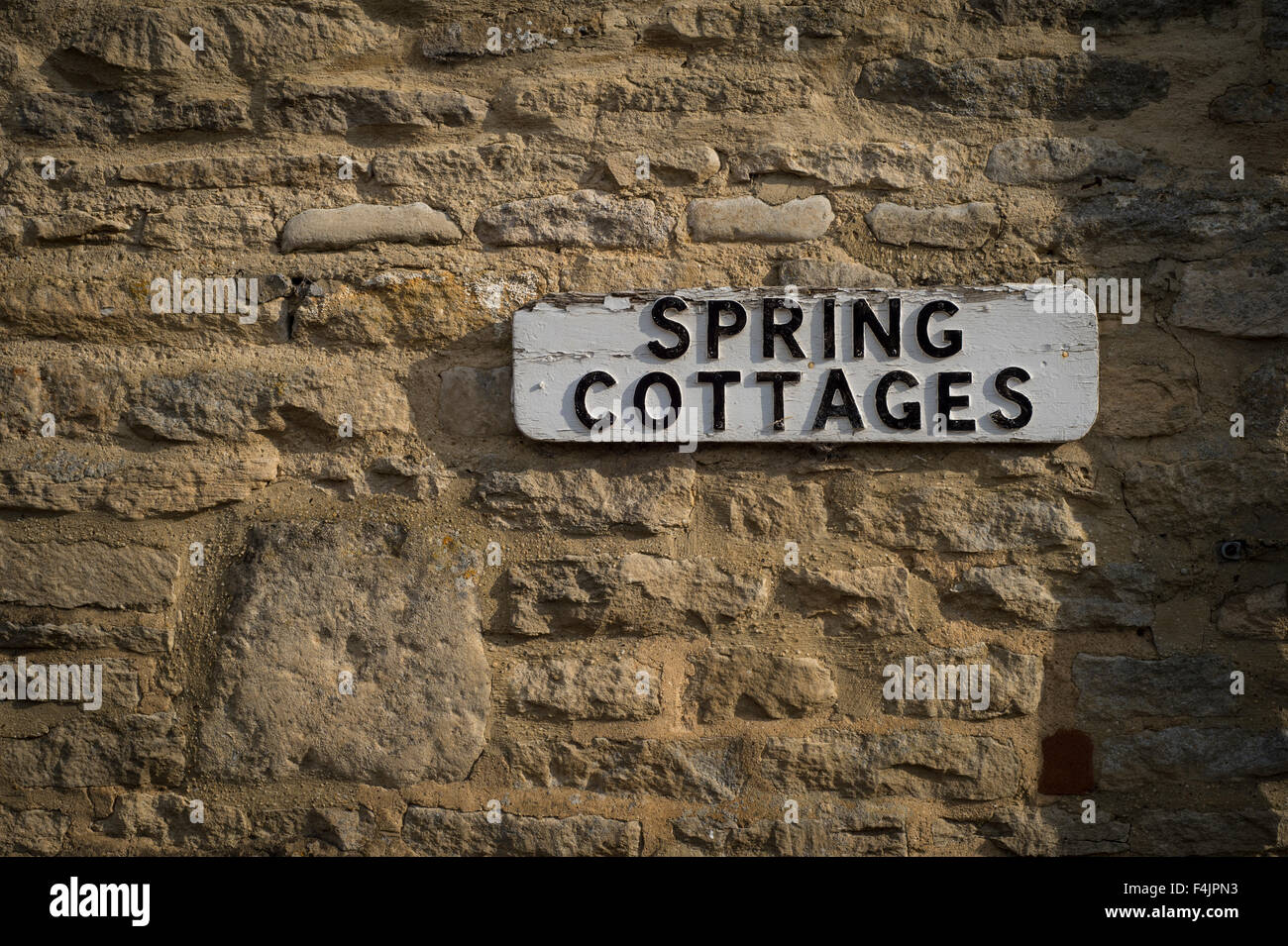 sign for Spring Cottages on a stone wall in the Cotswolds Stock Photo