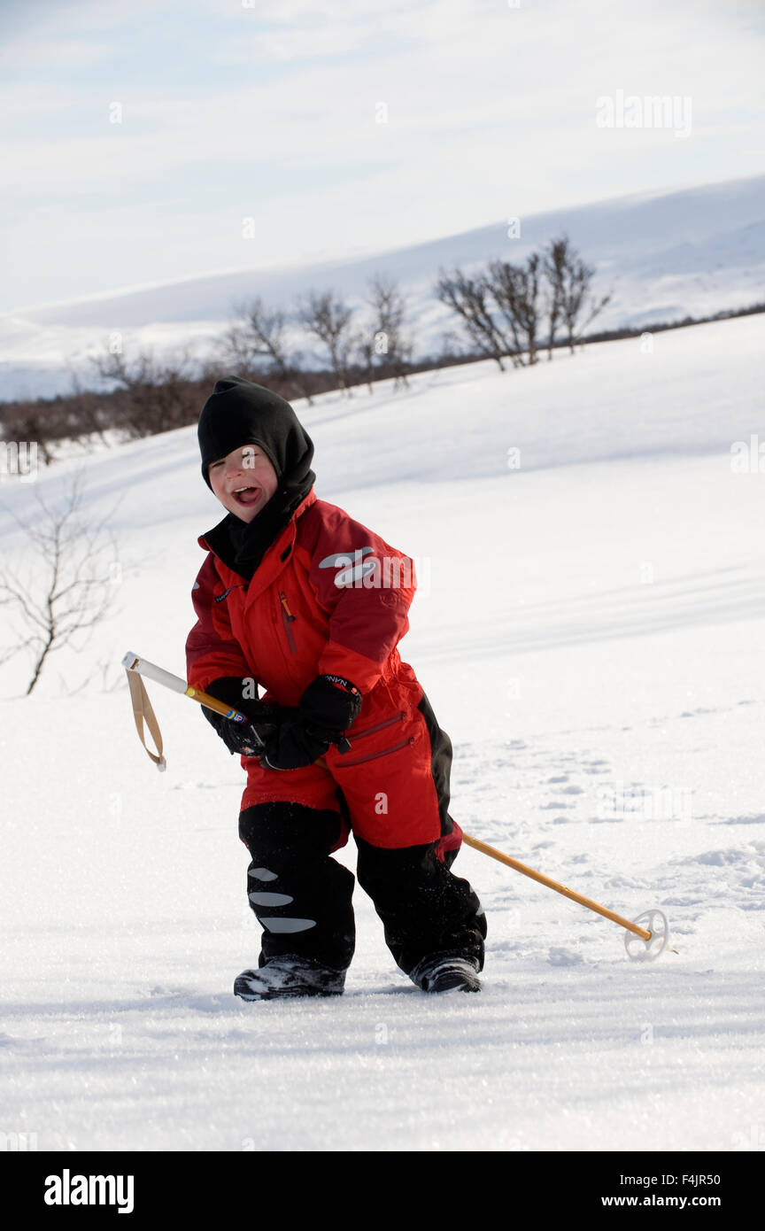 Boy playing with hiking pole in snow Stock Photo