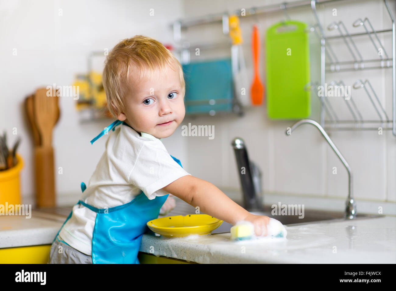 Child washing dishes in a domestic kitchen Stock Photo