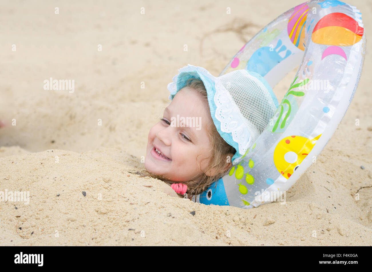 Fouryear girl buried in the sand on the beach with his head planted