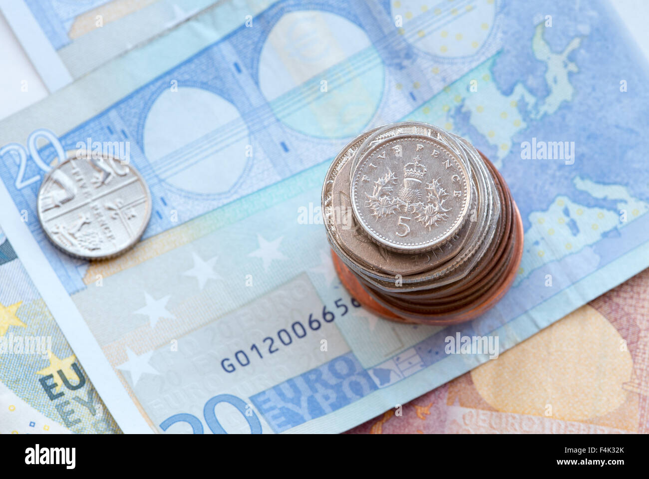 British five silver pence coin on a pile of coins and twenty Euro notes Stock Photo