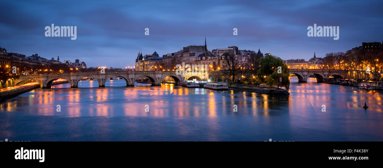 Ile de la Cite and Pont Neuf at dawn. The calm Seine River reflects the cloudy morning sky and street lamp lights. Paris, France Stock Photo