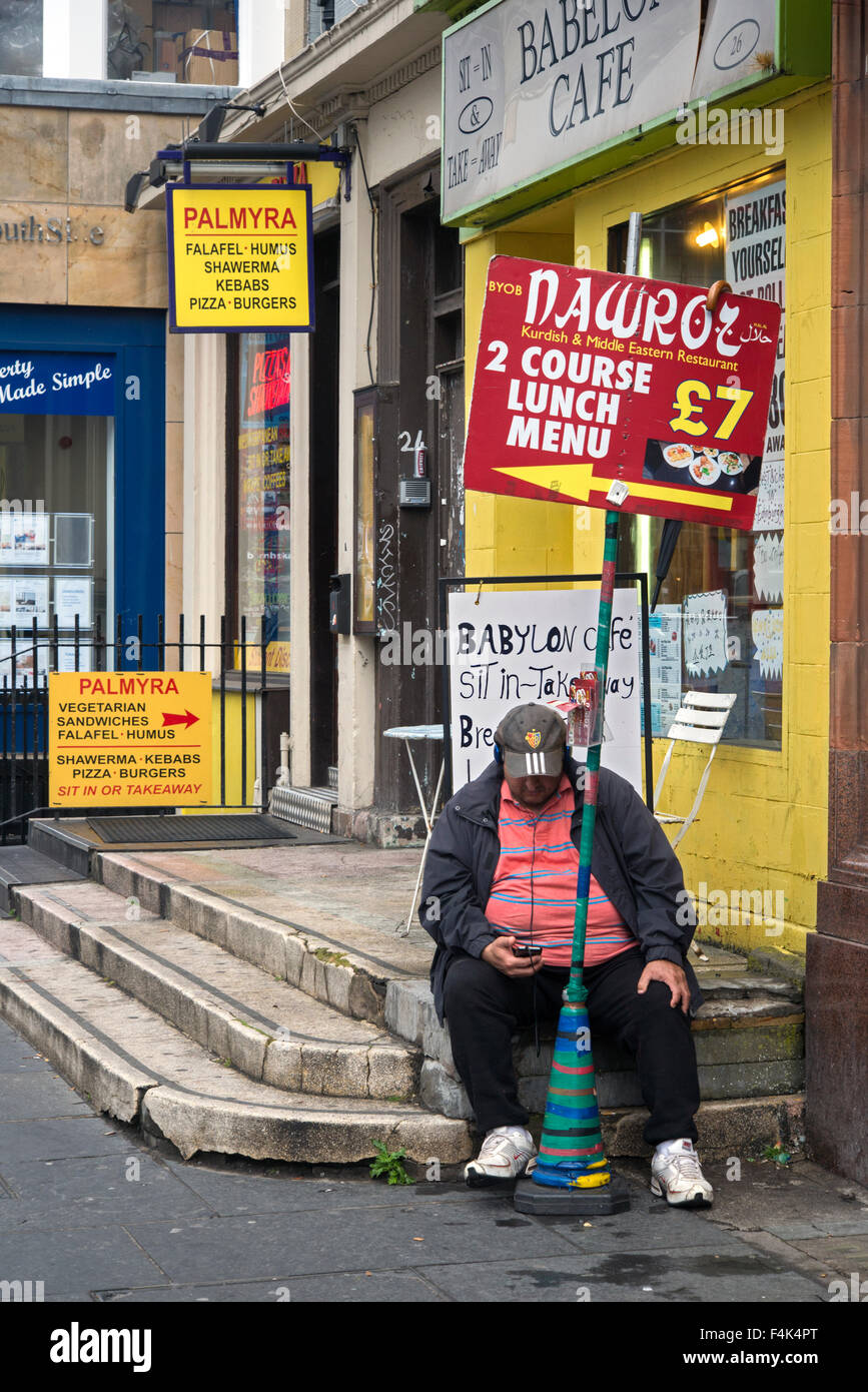 A rather portly gentleman checking his phone whilst holding a sign adverting a 2 course lunch for £7 in a nearby restaurant. Stock Photo