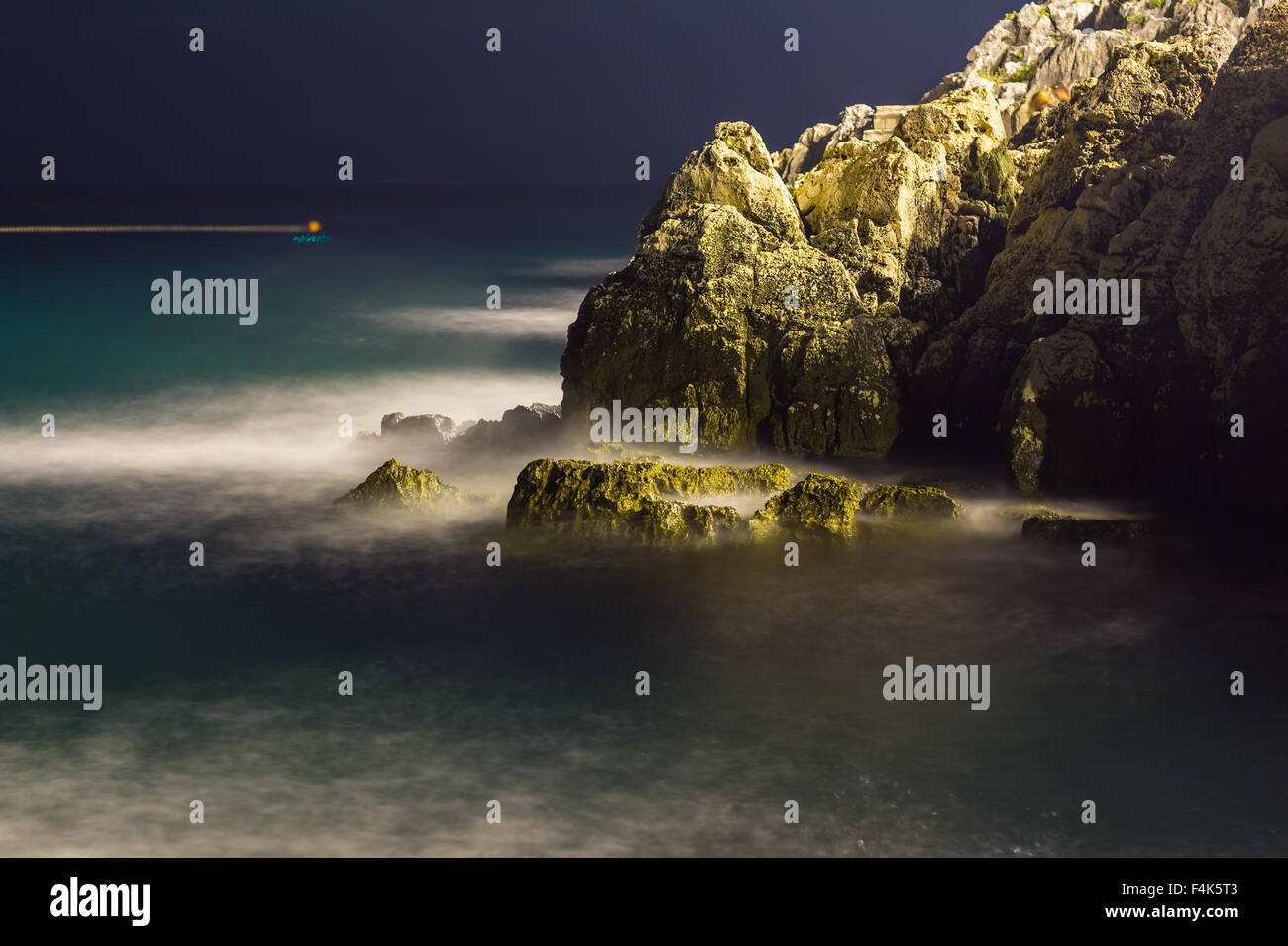 Sea waves lash line impact rock on the beach in night Stock Photo