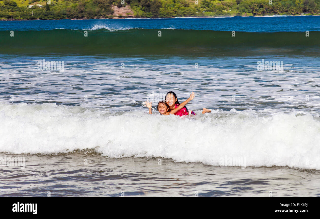 Brother and sister share boogie board at Hanalei Beach on Kauai Stock